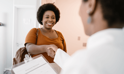 Female health care professional shaking hands with a female patient