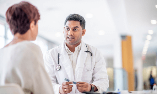 Diverse male health care professional showing a red-headed female patient how to use an insulin pen